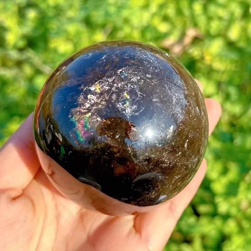 Polished Rainbow Smoky Quartz sphere with grounding brown tones and vibrant internal flashes for root chakra healing.