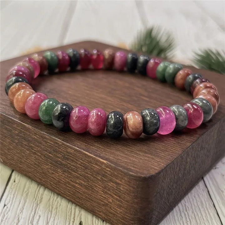 Handmade Rainbow Tourmaline beaded bracelet with vibrant, balancing gemstone beads on a wooden display stand.