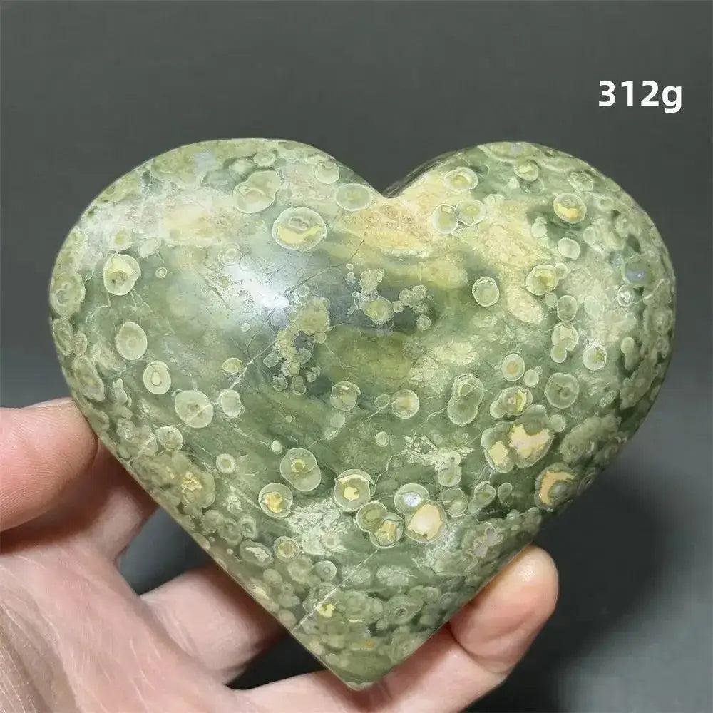 Rainforest Jasper Heart Healing Crystal, a unique green and yellow spotted Rhyolite heart, 312g, held in a hand.