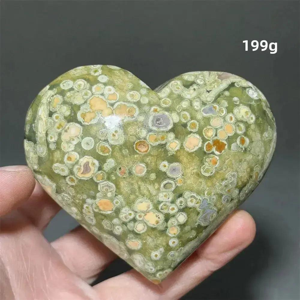 Hand holding a 199g Rainforest Jasper heart healing crystal from Crystal Destiny, featuring green, yellow, and brown patterns.