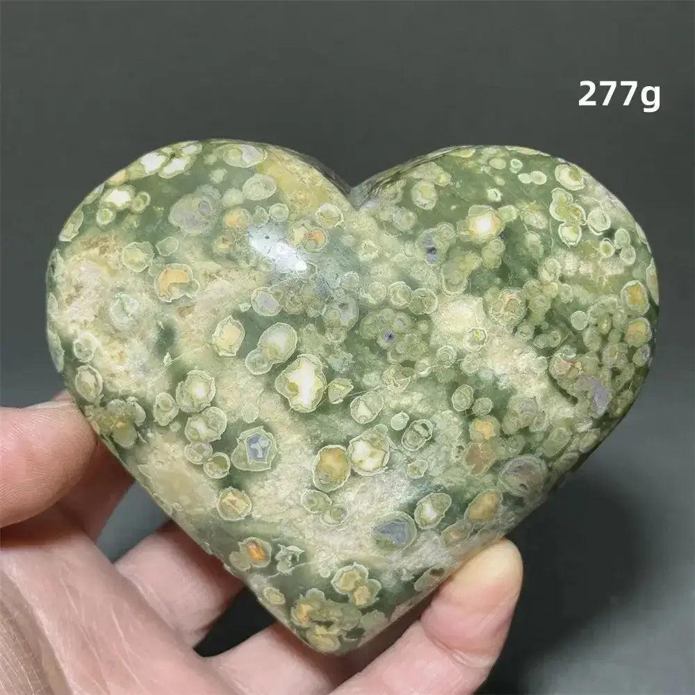 Hand holding a 277g Rainforest Jasper heart healing crystal from Crystal Destiny, featuring green, cream, and yellow patterns.