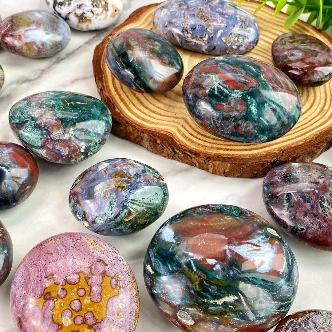 Polished Ocean Jasper palm stone with vibrant, swirling green, red, and pink patterns for healing and home decor.
