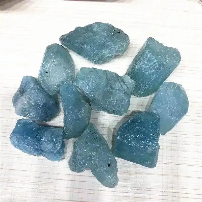 Raw aquamarine stones in cool sea blue, featuring natural rough textures and inclusions for Throat and Heart chakra healing.
