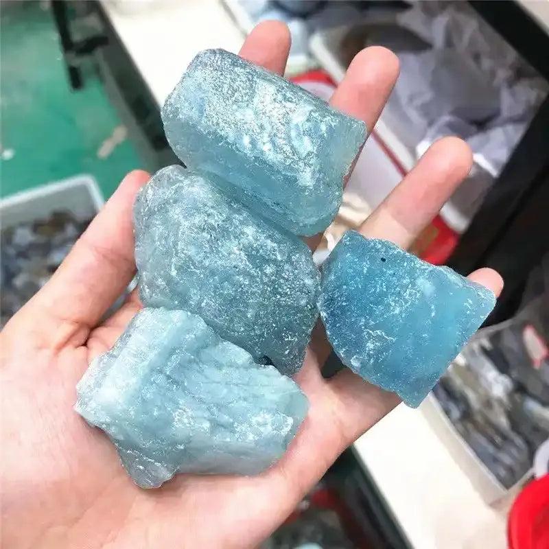 Raw aquamarine stones in cool sea blue, featuring natural rough textures and inclusions for throat chakra healing.