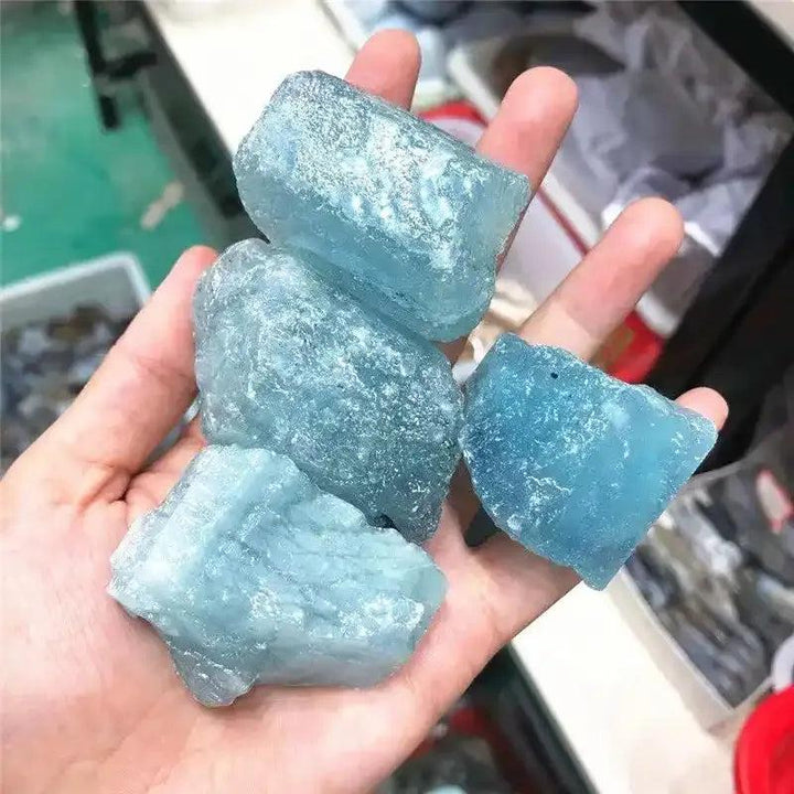 Raw aquamarine stones in cool sea blue, featuring natural rough textures and inclusions for throat chakra healing.