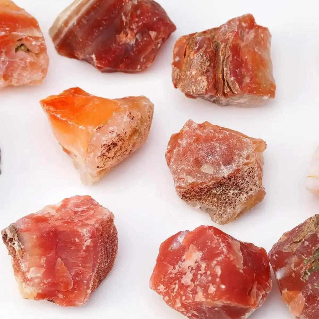 Raw Carnelian stones in warm orange and red-brown, featuring natural, unpolished textures for creative energy and courage.