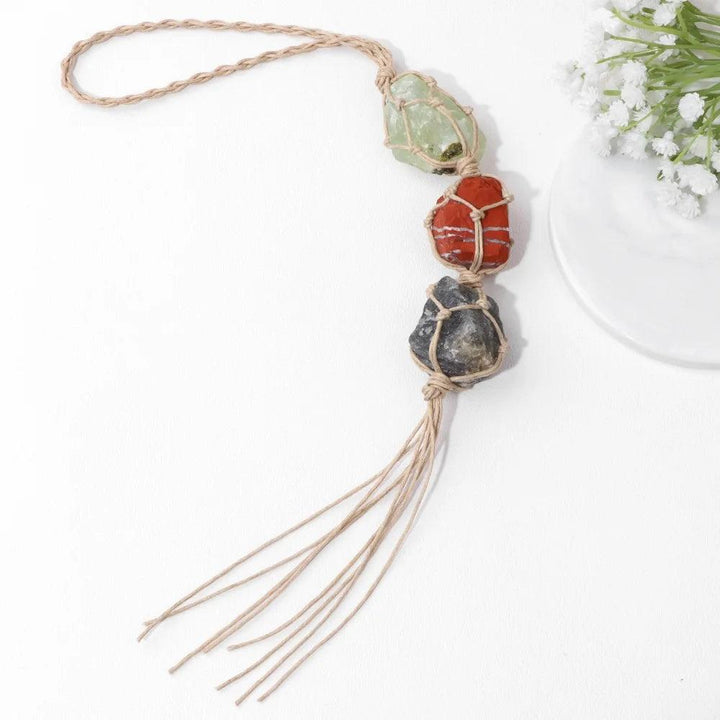 Macrame car pendant with three raw, irregular quartz stones: green, red, and dark grey, for interior decoration.