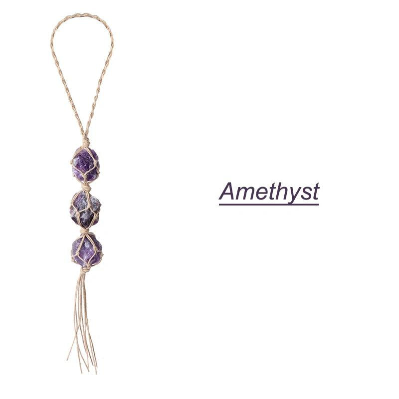 Three raw, irregular amethyst stones in macrame netting, forming a car rearview mirror pendant with a braided loop.