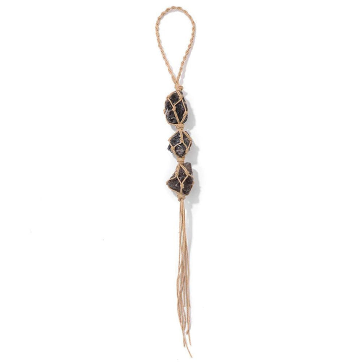 Natural raw quartz crystal car pendant with three dark, irregular stones in macrame netting on a braided jute cord.
