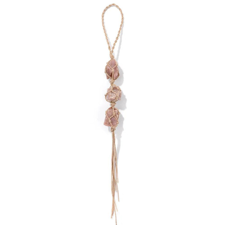 Three irregular raw pink quartz stones in macrame, hanging as a car rearview mirror pendant for interior decoration.