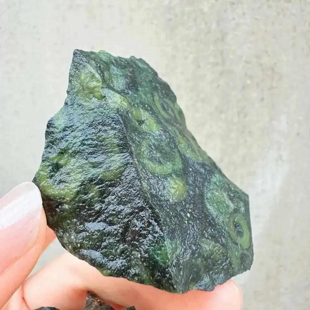 Raw Kambaba Jasper stone featuring dark green textures and natural black orb patterns for grounding and heart chakra healing.