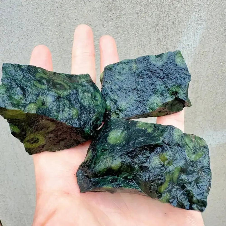 Raw Kambaba Jasper stones featuring dark green textures and natural black orbs for grounding and heart chakra healing.