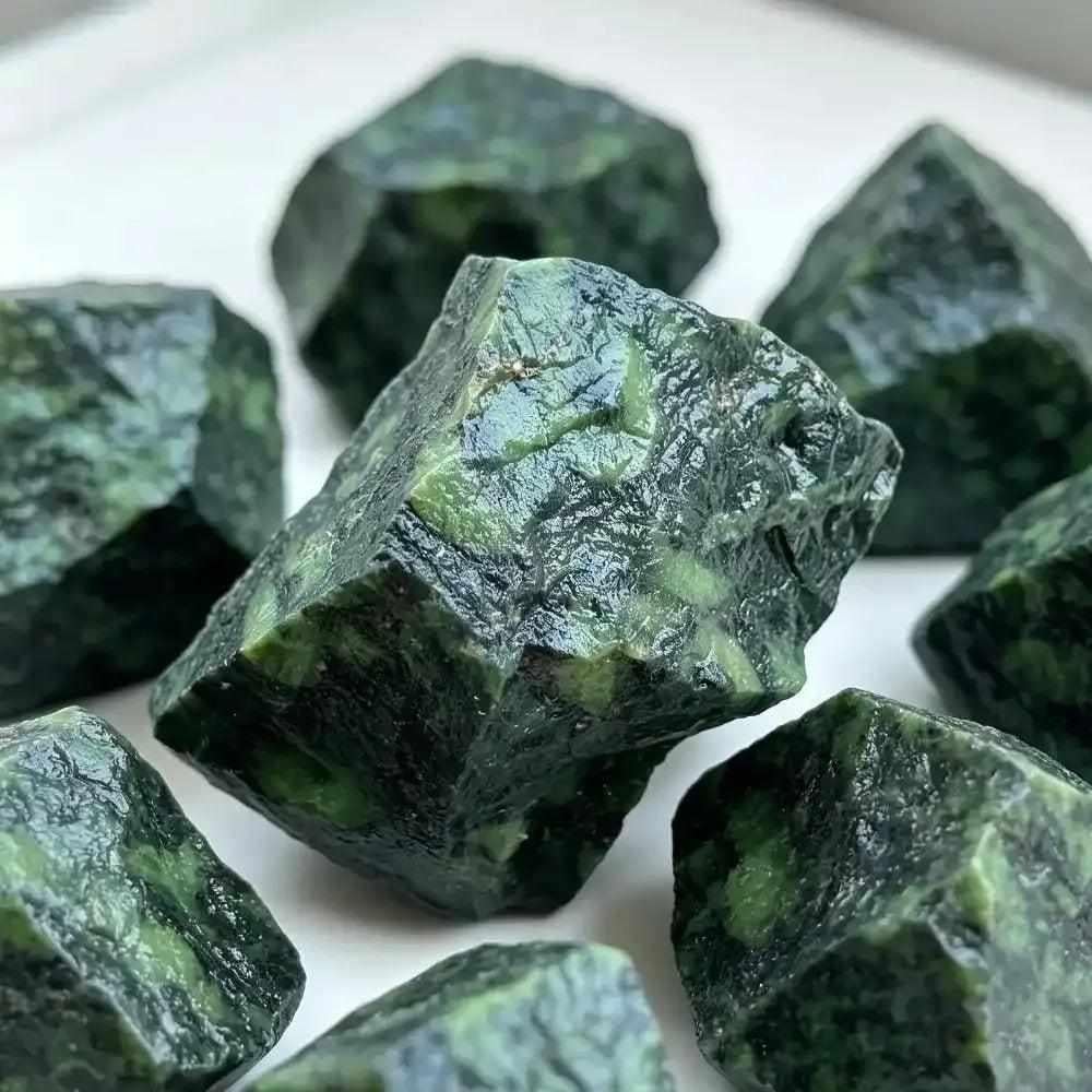 Raw Kambaba Jasper stones featuring earthy dark green textures and black orbs for grounding and heart chakra healing.