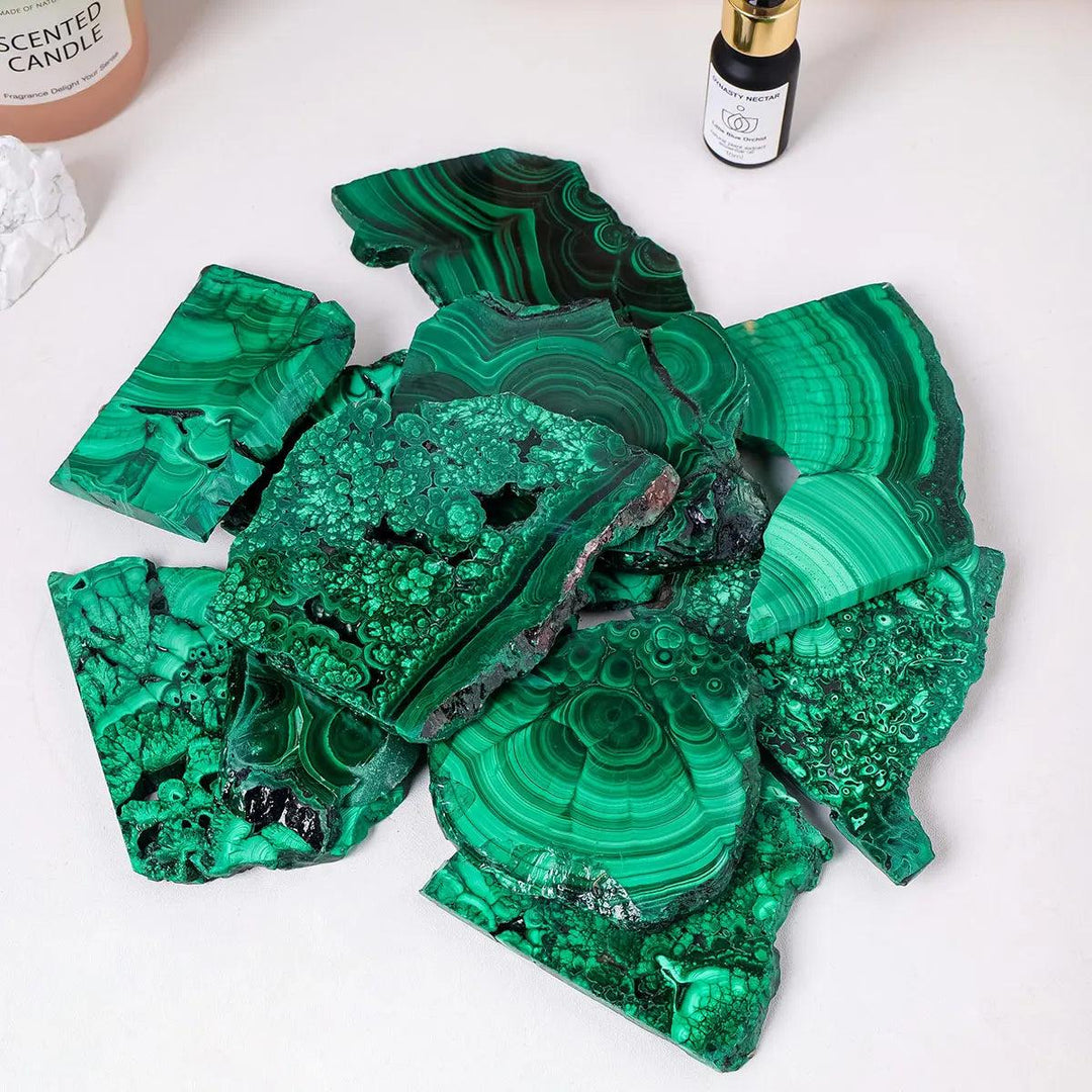 Raw Malachite pieces featuring vivid green bands and natural eye-like rings, perfect for Heart Chakra transformation.