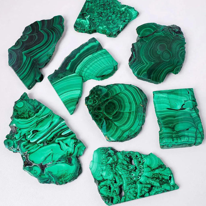 Raw malachite pieces featuring vivid green bands and eye-like rings, perfect for heart chakra healing and home decor.