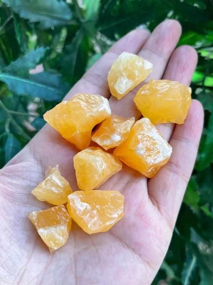 Raw orange calcite stones with a waxy glow, perfect for sacral chakra healing and creative energy in a natural rough form.