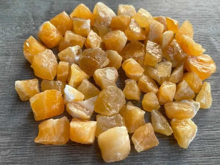 Raw orange calcite stones with a bright, waxy glow, perfect for sacral chakra energy and creative home decor accents.