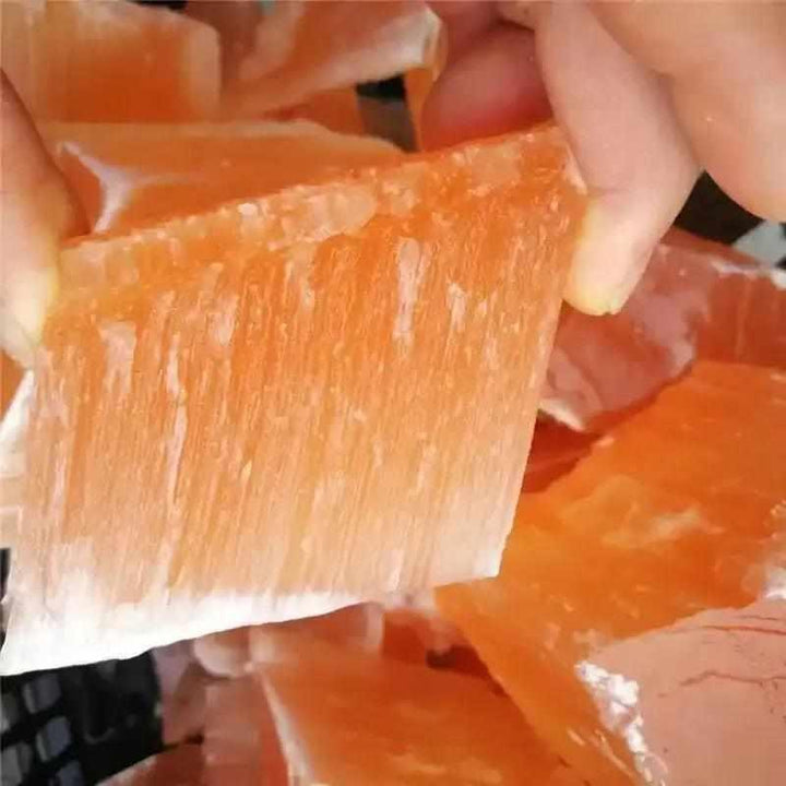 Raw orange selenite chunk with silky, fibrous texture and warm peach tones, perfect for sacral chakra energy cleansing.