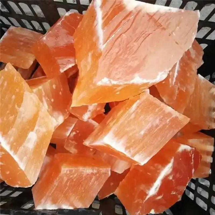 Raw orange selenite chunks with silky, peach-toned fibers for sacral chakra cleansing and creative inspiration.