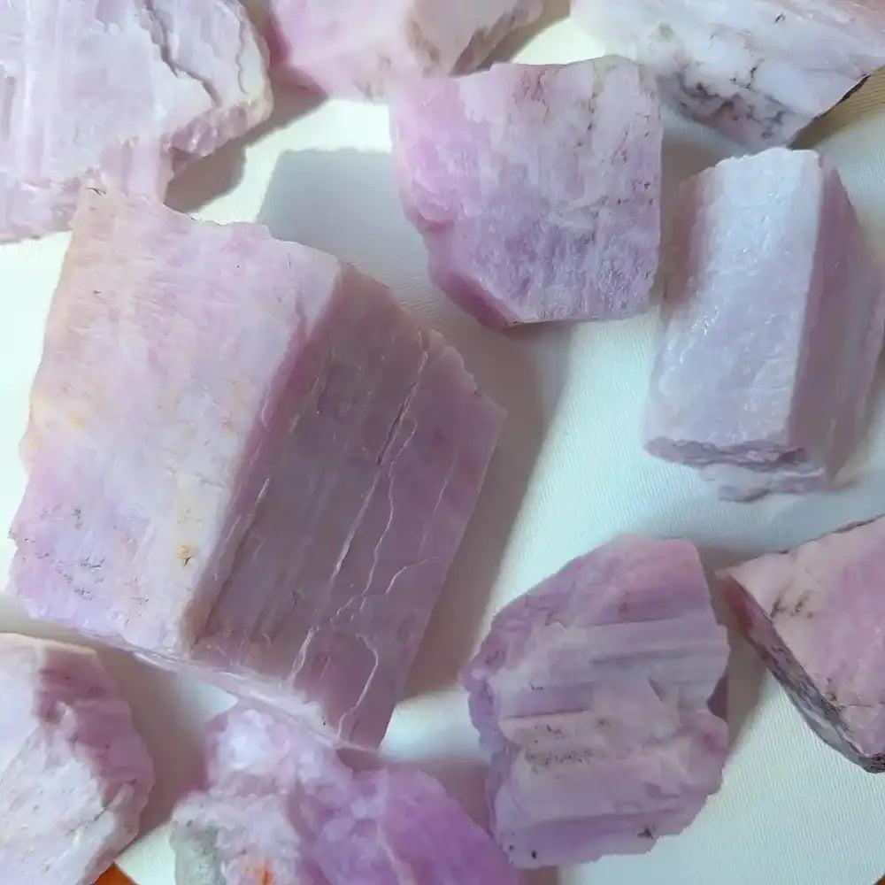 Raw pink Kunzite stones with glassy luster and natural, unpolished textures for heart chakra healing and meditation.
