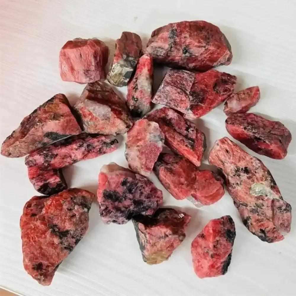 Raw rhodonite stones featuring rosy pink hues and natural black veins, perfect for heart chakra healing and meditation.