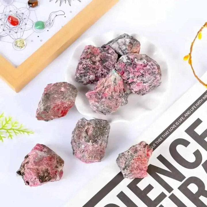 Raw Rhodonite stones featuring rosy pink hues and natural black veins, perfect for Heart chakra healing and meditation.