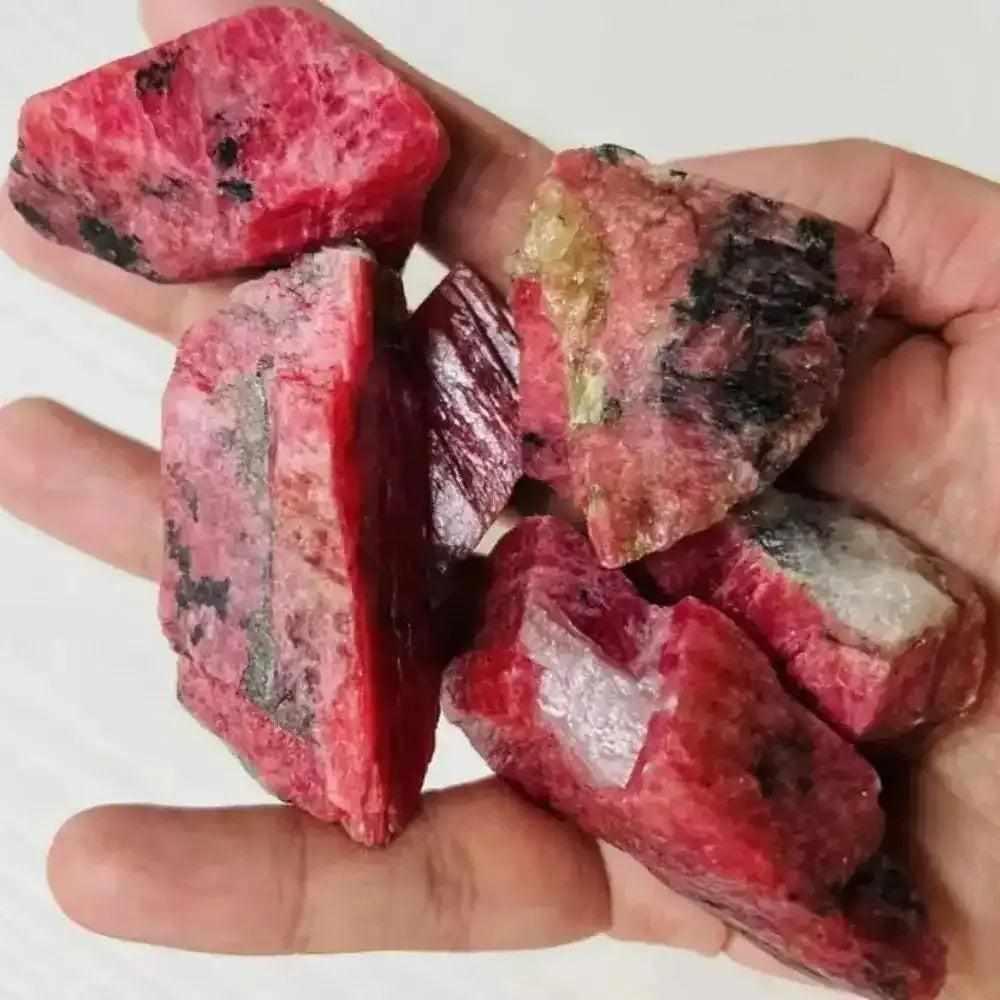 Raw rhodonite stones with vibrant pink hues and black veins, perfect for heart chakra healing and emotional balance.