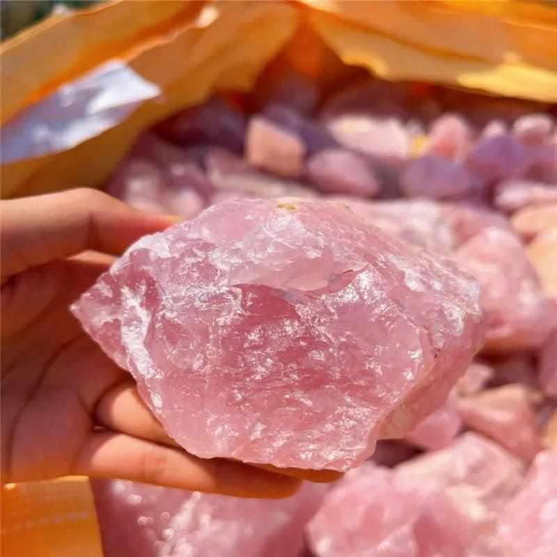 Hand holding a raw, unpolished piece of soft pink rose quartz, perfect for heart chakra healing and natural home decor.