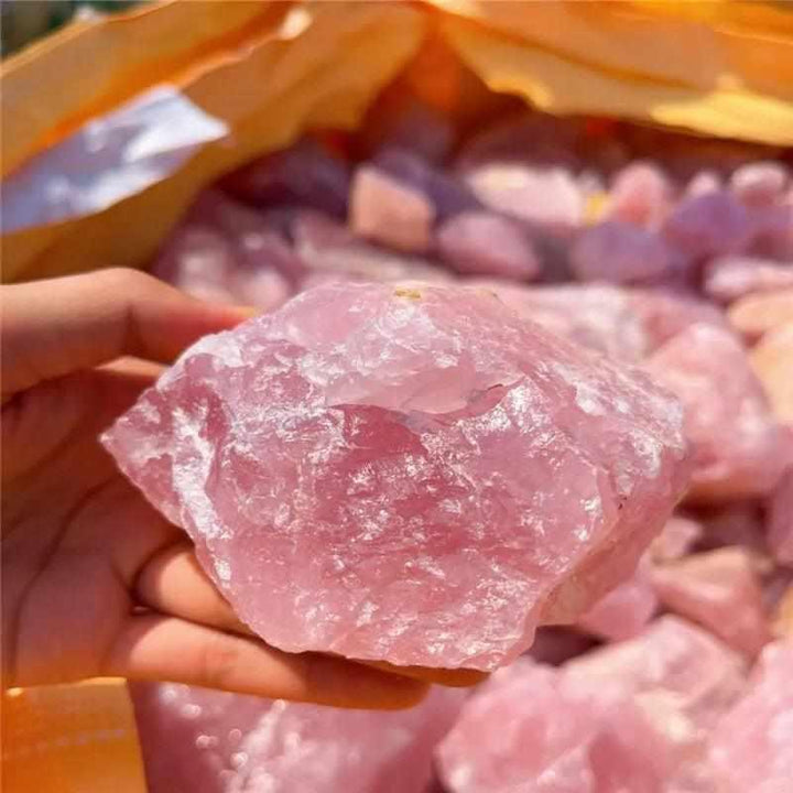 Hand holding a raw, unpolished piece of soft pink rose quartz, perfect for heart chakra healing and natural home decor.