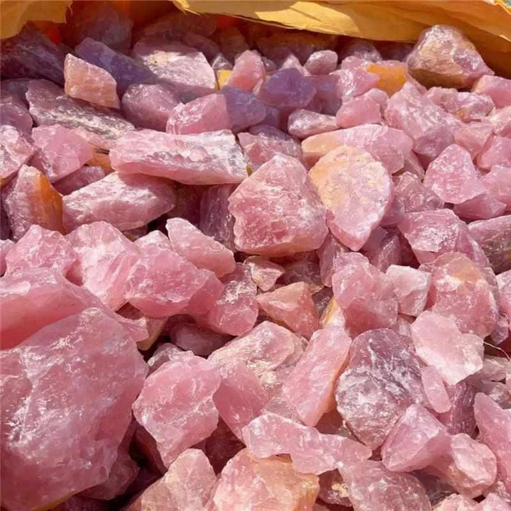 Raw rose quartz stones with natural rough surfaces and soft pink hues, perfect for heart chakra healing and home decor.
