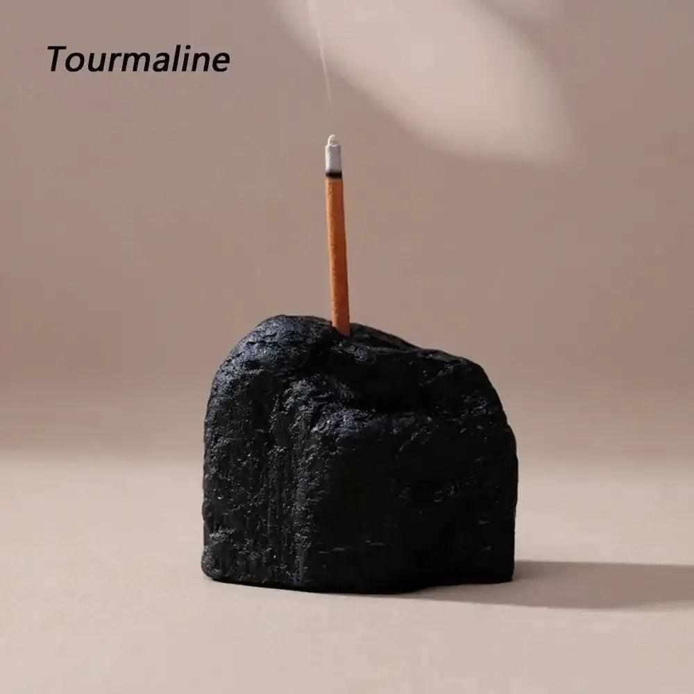 Rough black tourmaline stone incense holder with a raw, textured surface for grounding rituals and mindful meditation.