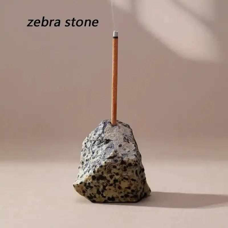 Raw Zebra Stone incense holder with a rough, speckled texture and a drilled opening for a slender incense stick.