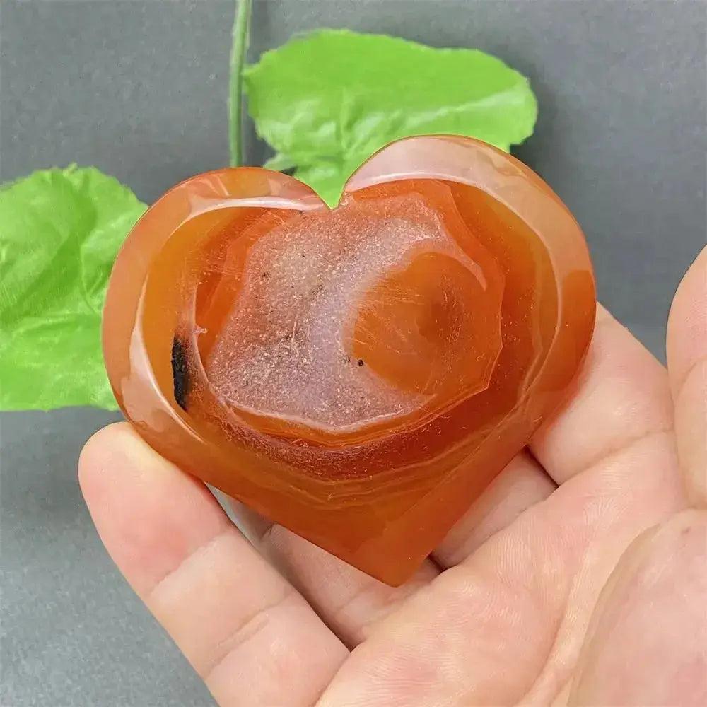 Natural Red Agate Heart Geode, polished red and earthy tones with sparkling druzy crystals, held in a hand.