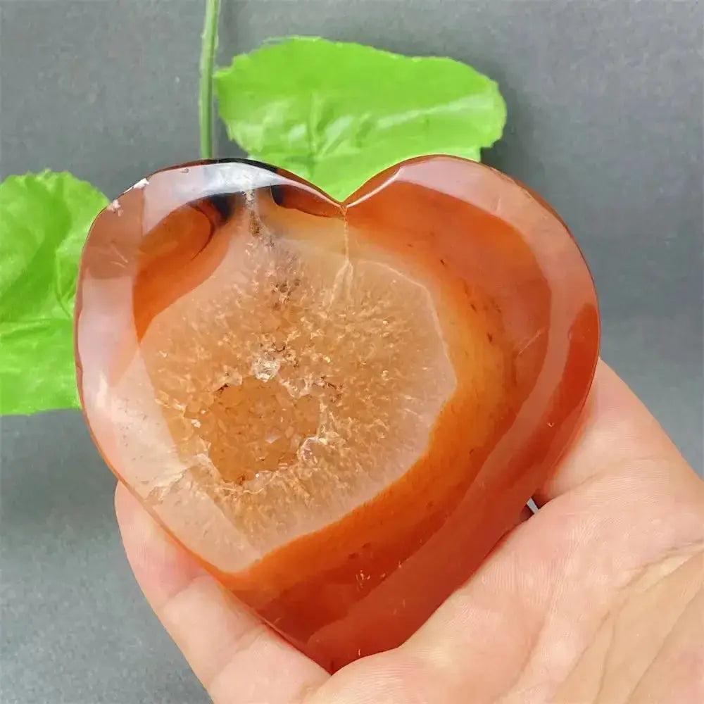 Natural Red Agate Heart Geode: Polished red agate heart with sparkling druzy crystal interior, held in hand.