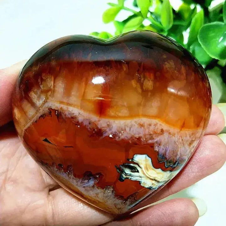 Polished Red Agate heart, a grounding vitality stone with rich red tones and natural banding, held in a hand.