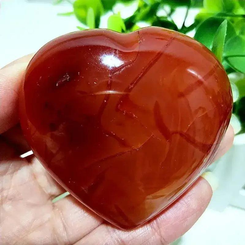 Polished Red Agate Heart, a grounding vitality stone for root chakra activation, held in a hand.