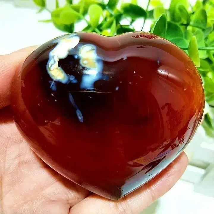 Polished Red Agate Heart, a grounding vitality stone with rich red tones and natural white banding, held in a hand.