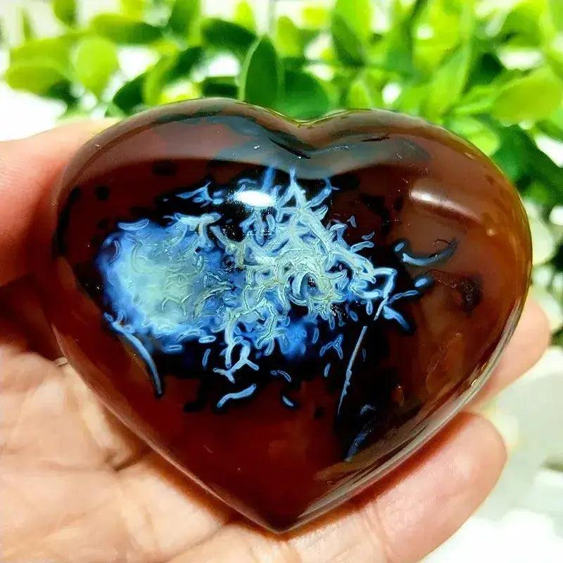 Polished Red Agate Heart, a grounding vitality stone with unique blue and white patterns, held in a hand.