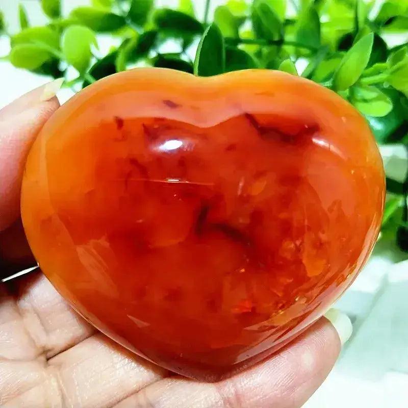 Polished Red Agate Heart, a vibrant Root Chakra grounding vitality stone, held in a hand.