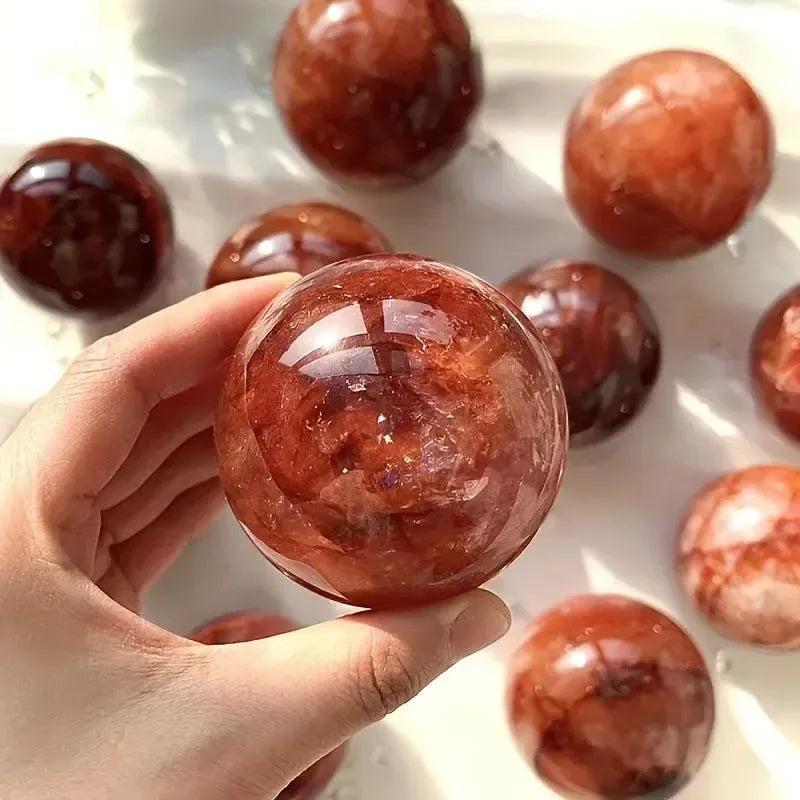Hand holding a vibrant Red Hematoid Fire Quartz Sphere with fiery red and orange inclusions, radiating passionate energy.