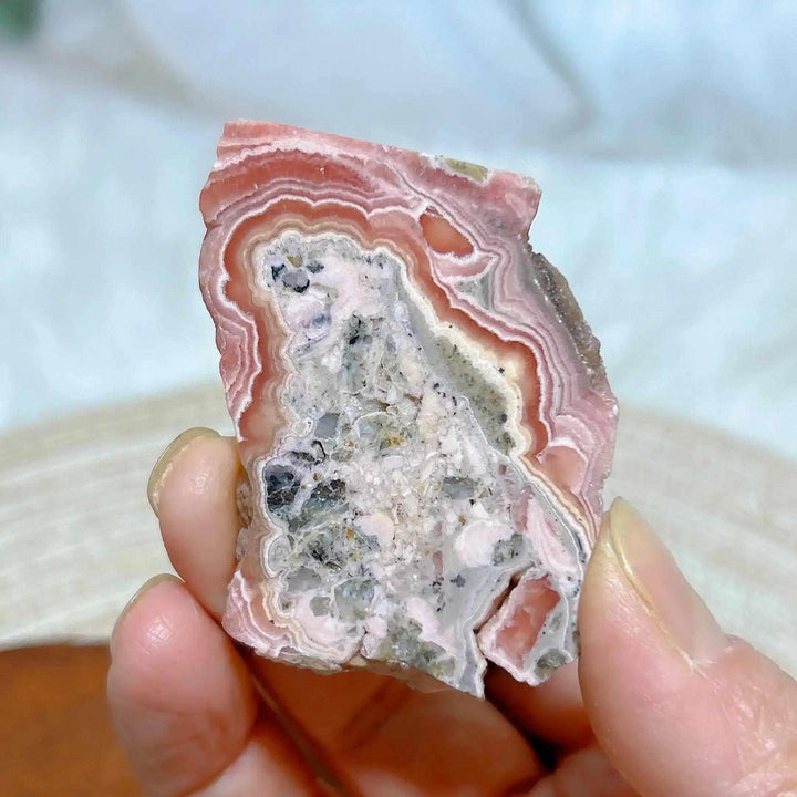 Polished Rhodochrosite raw slab featuring raspberry pink banding and a textured center for heart chakra healing.