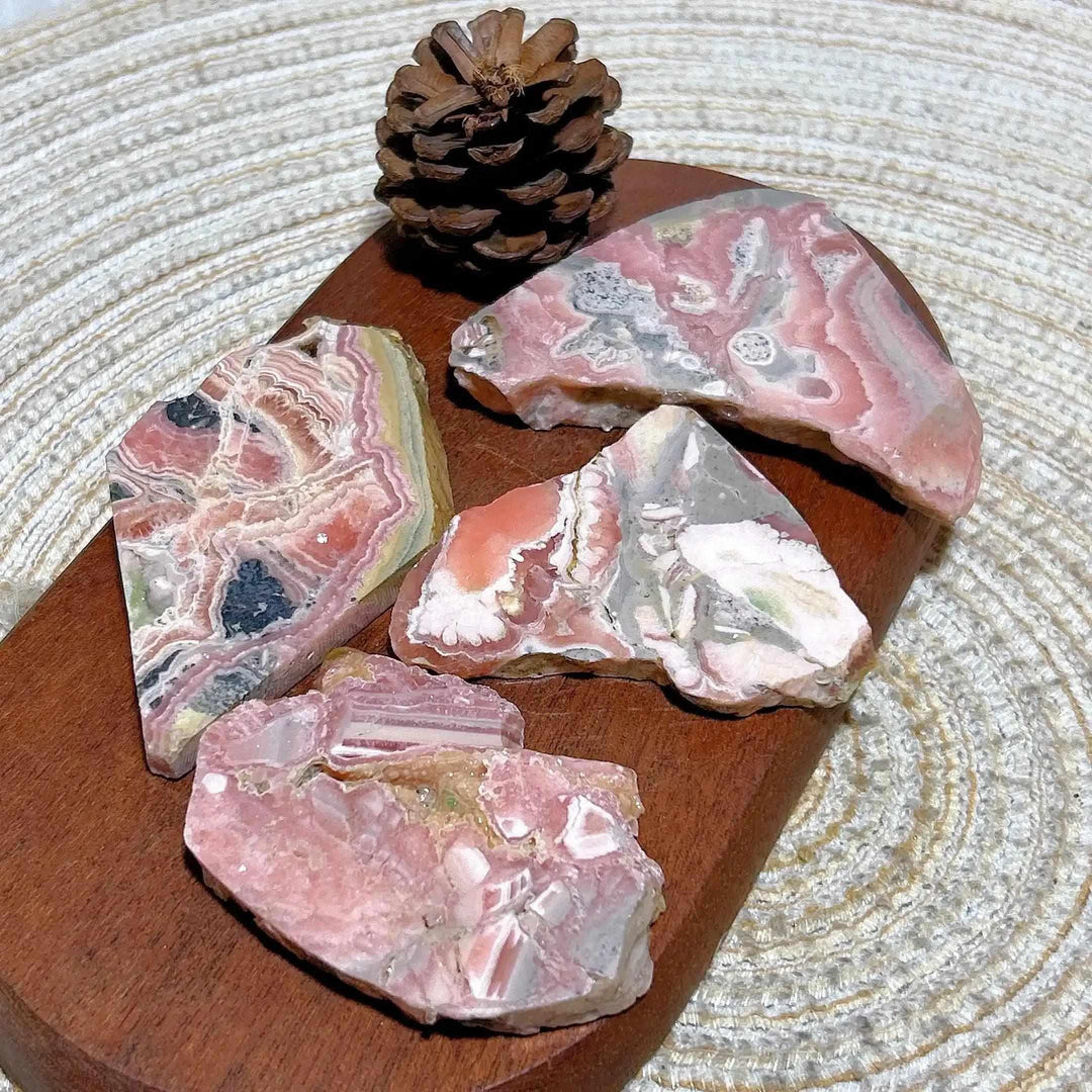Polished Rhodochrosite raw slabs featuring rose-pink banding and natural edges for heart chakra healing and display.