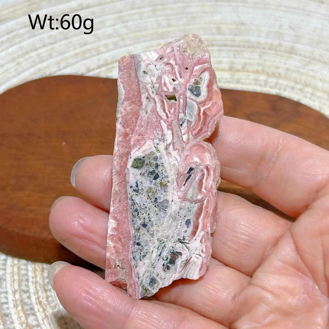 Polished Rhodochrosite raw slab featuring raspberry pink banding and natural textures for heart chakra healing and display.