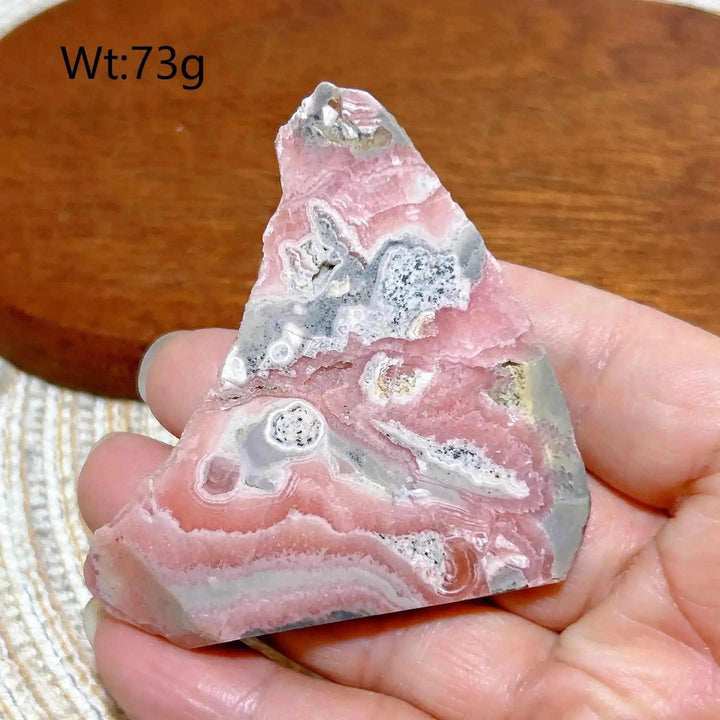 Polished Rhodochrosite raw slab featuring rose pink and raspberry banding for heart chakra healing and display.