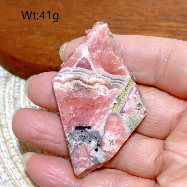 Polished Rhodochrosite raw slab featuring raspberry pink banding and natural edges for heart chakra healing and display.