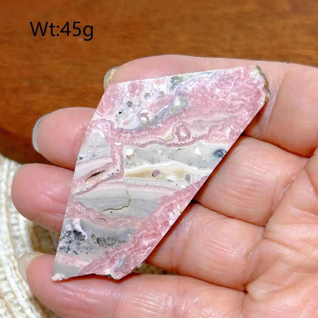 Polished Rhodochrosite raw slab featuring rose-pink banding and natural edges for heart chakra healing and display.