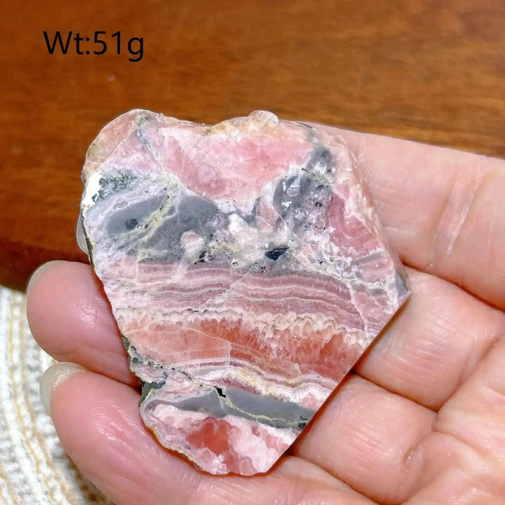 Polished Rhodochrosite raw slab featuring raspberry pink banding and natural edges for heart chakra healing and display.
