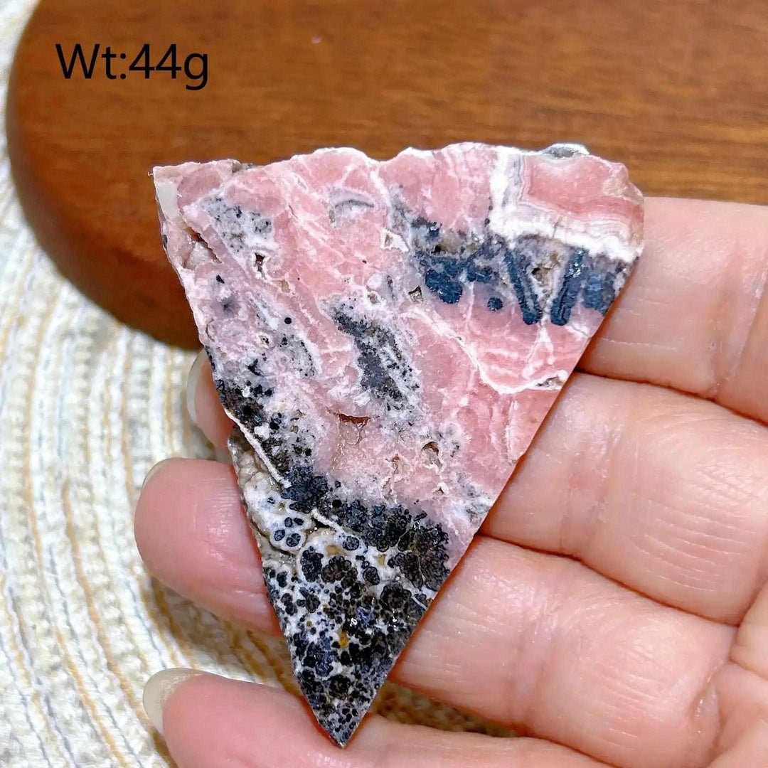 Polished Rhodochrosite raw slab featuring rose-pink banding and dark mineral inclusions for heart chakra healing.