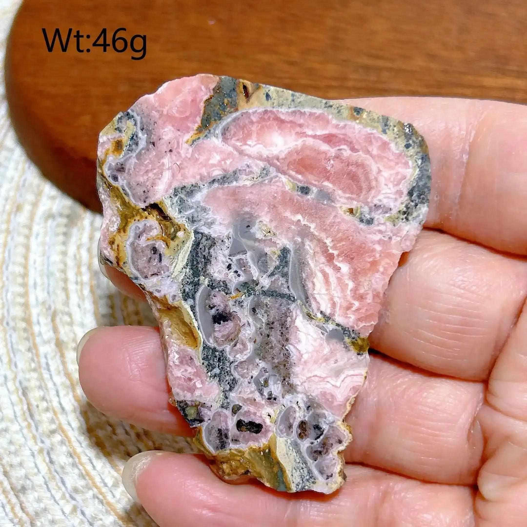 Polished Rhodochrosite raw slab featuring rose-pink banding and natural edges for heart chakra healing and display.