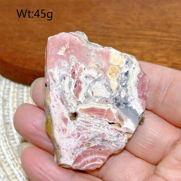 Polished Rhodochrosite raw slab featuring rose-pink banding for emotional healing and self-love.